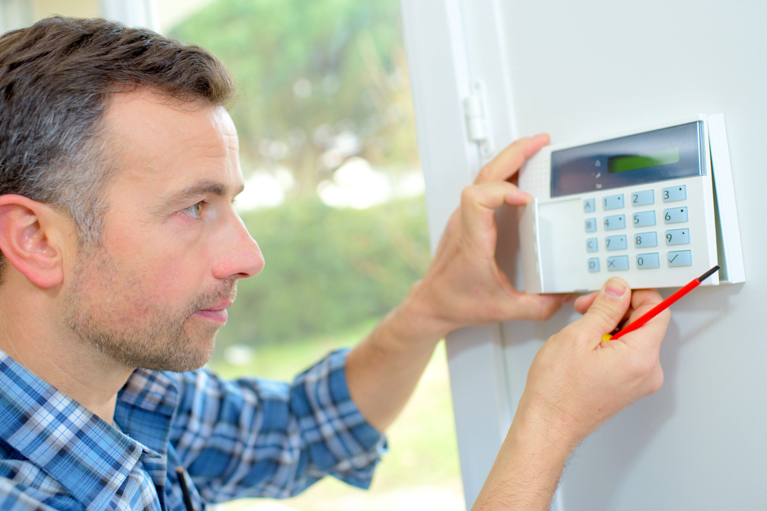 Electrician fitting an intrusion alarm